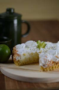 A delicious key lime pie with whipped cream on a wooden board, perfect for dessert lovers.