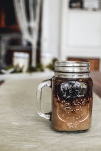 Refreshing iced coffee served in a mason jar placed on a cozy table setting indoors.